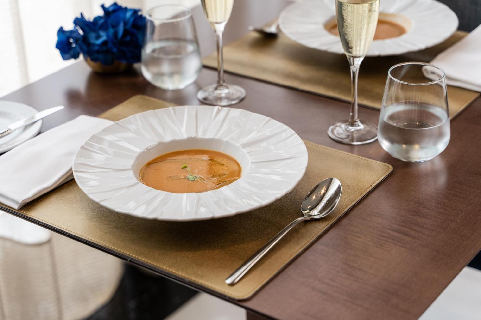 Eurostars Universal Lisboa מראה חיצוני תמונה The photo displays an elegant dining setting. In the center, there's a large white plate with a decorative edge, containing a serving of soup, garnished with a few sprigs of herbs. Surrounding the plate, there are two glasses of sparkling wine, and a