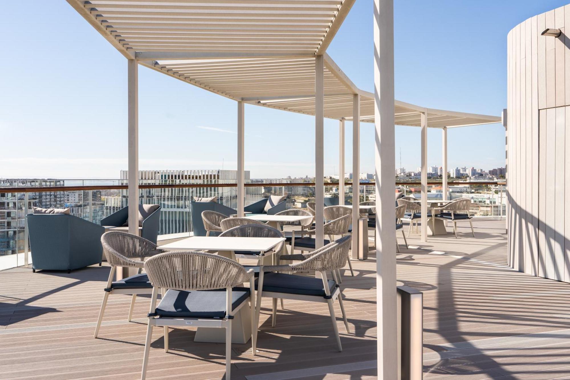Eurostars Universal Lisboa מראה חיצוני תמונה The photo shows a rooftop terrace with a modern design. It features several covered seating areas with tables and chairs, arranged for dining or lounging. The furniture appears to be stylish and comfortable, with some matches of cushions and throws. 